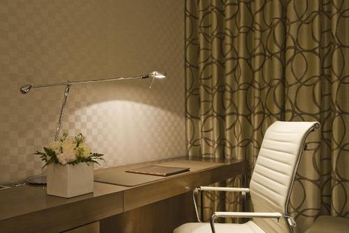 a desk with a white chair and a desk with a lamp at LOTTE CITY HOTEL Mapo in Seoul