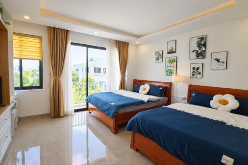 a bedroom with two beds and a television at Sunhouse Villa Huế in Hue