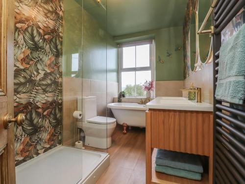 a bathroom with a tub and a toilet and a sink at Canalside Cottage in Kildwick