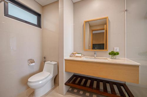 a bathroom with a toilet and a sink and a mirror at The Bada studio apartment - ocean view in Danang