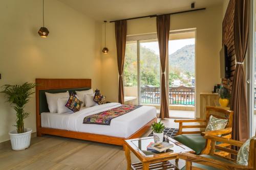 a bedroom with a bed and a balcony at Tripli Hotels Sukritham in Narendranagar