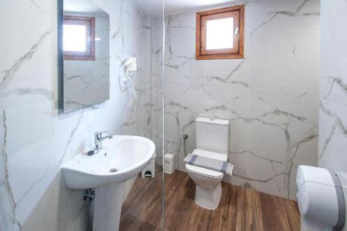 a white bathroom with a sink and a toilet at Grecos ZERO SKIATHOS in Skiathos