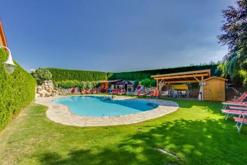 a swimming pool in a yard with chairs and a pavilion at Hotel Hubertushof in Natz-Schabs