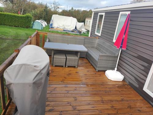 a deck with a bench and a table and an umbrella at Huis-Meerwijck in Kropswolde