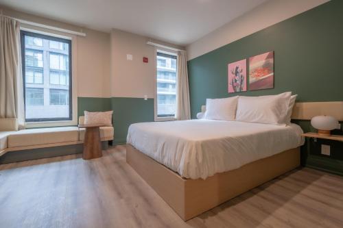 a bedroom with a large bed and two windows at Hotel Beebop in Toronto