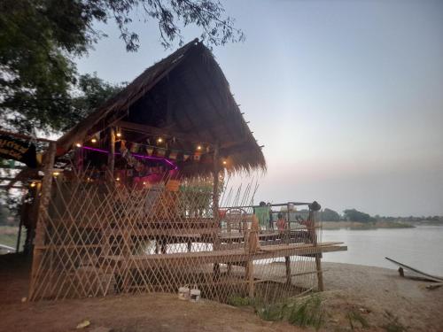 a hut on the shore of a body of water at Champasak Backpacker in Ban Mouang