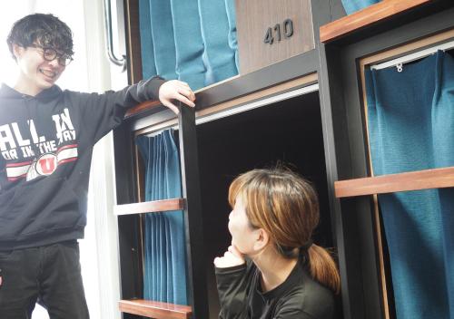 a man and a woman looking out of a window at Hostel JAZ in Tokyo