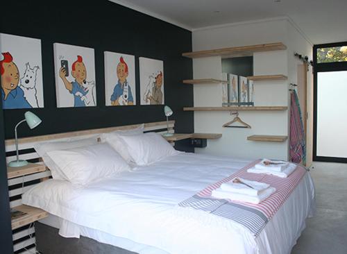 ein Schlafzimmer mit einem großen weißen Bett mit Bildern an der Wand in der Unterkunft No. 9 Keurboom in Kapstadt