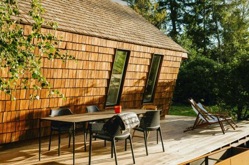 a table and chairs on a deck with a building at Architectural Tiny House With Sauna Near Beach in Asnæs