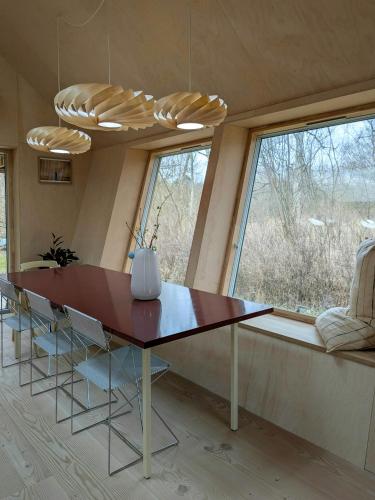 a dining room with a table and a large window at Architectural Tiny House With Sauna Near Beach in Asnæs