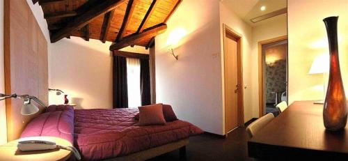 a bedroom with a bed with a purple blanket and a desk at Relais Villa D'Assio in Labro Rieti