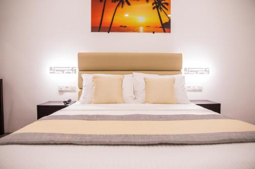 um quarto com uma cama grande com lençóis brancos e almofadas em Venue Colombo em Colombo