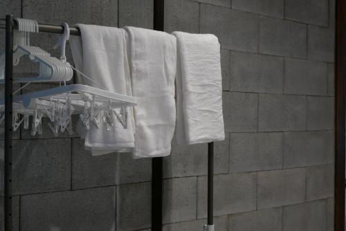 a group of white towels hanging on a rack in a bathroom at Tonoda Guesthouse Kyoto 殿田宿 Private 2-Story Home in Kyoto
