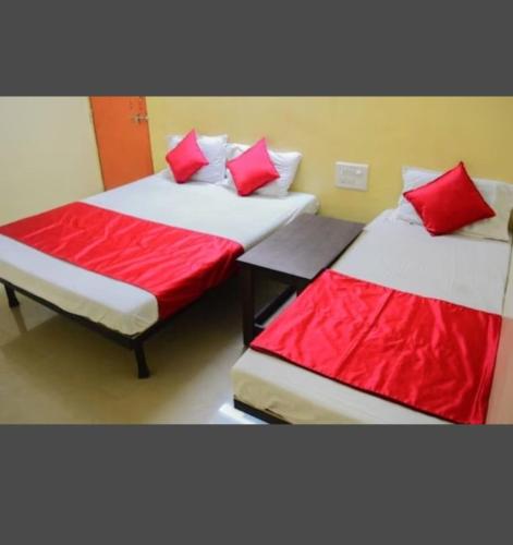 two beds in a room with red and white pillows at Sai Gaurav Palace in Shirdi
