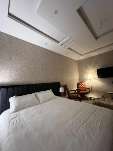 a bedroom with a large white bed and a chair at ملاذ للشقق المفروشة 2 in Tabuk