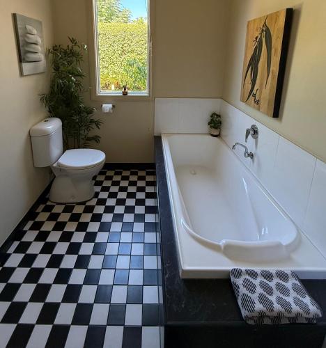 a bathroom with a bath tub and a toilet at Lotte's Cottage in Broken Hill