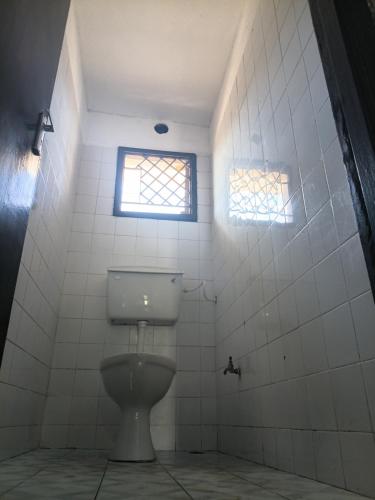 a bathroom with a toilet and two windows at Honeymoon villa Diani in Diani Beach