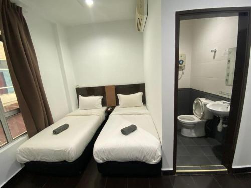 two beds in a room with a toilet and a mirror at Hotel O Friend in Petaling Jaya