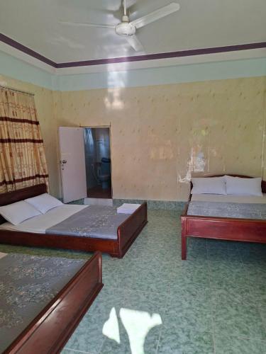 a bedroom with two beds and a ceiling fan at Homestay Hồng Hoa in Hà Tiên