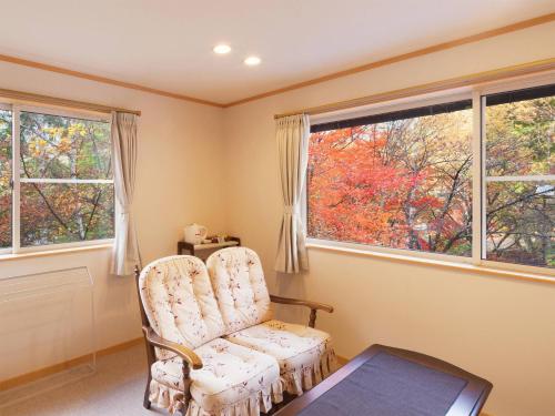 a room with a chair and a table and two windows at Nakaodaira in Takayama