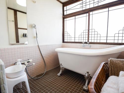 a bathroom with a bath tub and a sink at ノキシタ in Hokuto