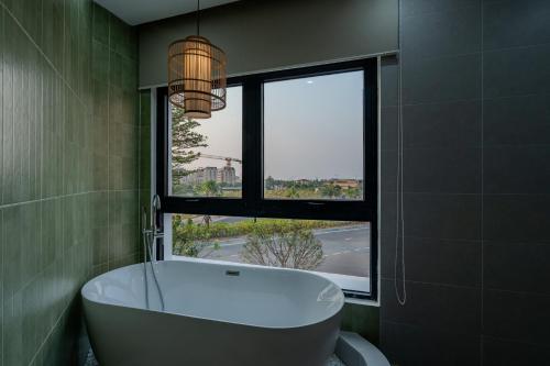 a bathroom with a bath tub and a window at Mana Hotel Quảng Bình in Dong Hoi