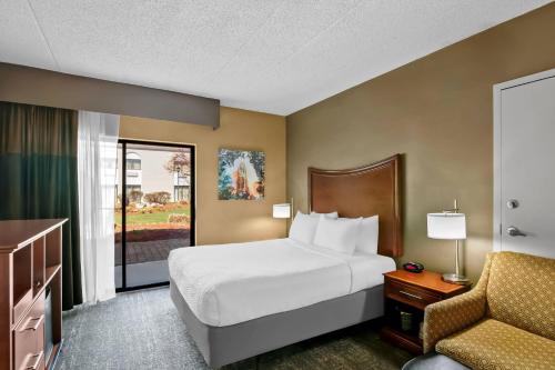 a hotel room with a bed and a chair at Clarion Inn North Haven - New Haven North in North Haven