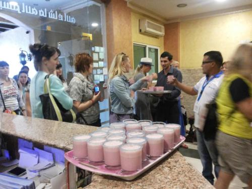 eine Gruppe von Menschen, die um einen Tisch mit rosa Milchgläsern stehen in der Unterkunft Al Qidra Hotel & Suites Aqaba in Aqaba