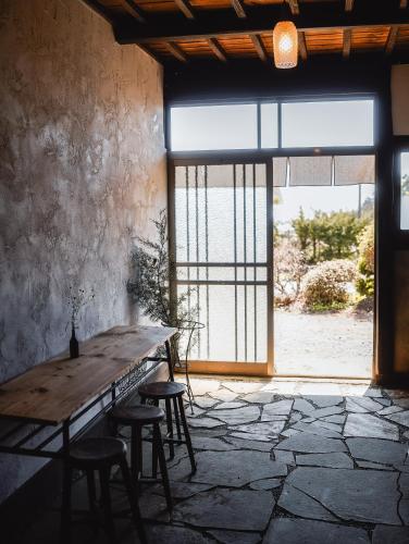 a wooden table and stools in a room with a large window at ノキシタ in Hokuto