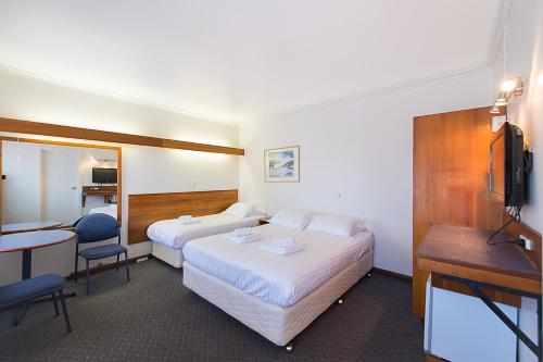 a hotel room with two beds and a desk at Blue Hills Motel in Hobart