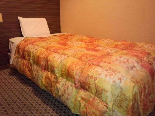 a bed in a hotel room with a colorful blanket at Hotel Matsumoto Hills in Matsumoto