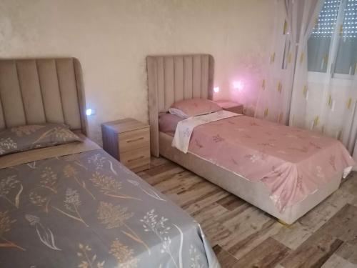 a bedroom with two beds and a wooden floor at Résidences nour nador in Nador