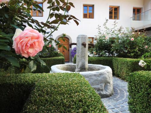 a garden with a pink rose and a stone fountain at Frühstückspension Herzog zu Laah in Linz