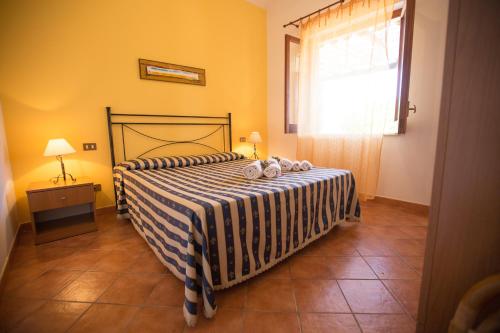 Un dormitorio con una cama con una manta de rayas y una ventana. en Villa Chiara, en Scopello
