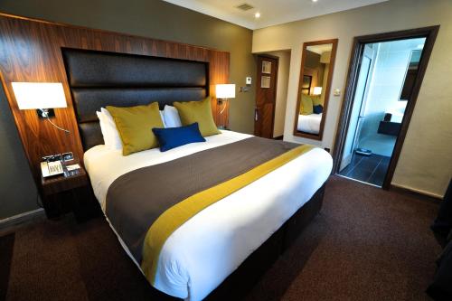 a large bed in a hotel room with two lamps at Frensham Pond Country House Hotel & Spa in Farnham