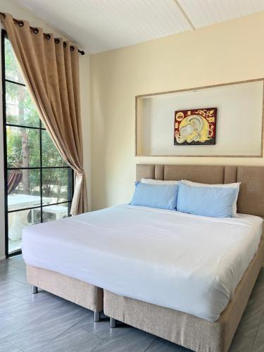 a bedroom with a large white bed with blue pillows at บ้านต้นลมสุวรรณภูมิ Baantonlom suvarnabhumi in Ban Khlong Thewa