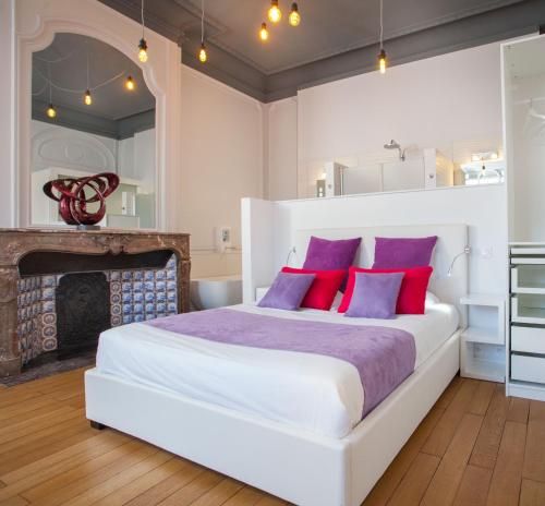 a bedroom with a white bed with red and purple pillows at L'Esplanade Lille in Lille