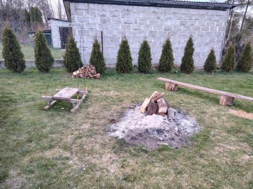 a fire pit with a bench and logs in a yard at Domek NAD RZEKA in Korczew