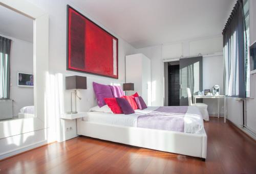 a bedroom with a white bed with red and purple pillows at L'Esplanade Lille in Lille