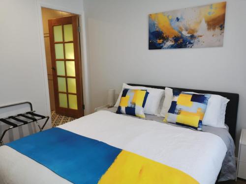 a bedroom with a bed with blue and yellow pillows at Creekside Cottage - Private Studio with Mountain View in Coffs Harbour