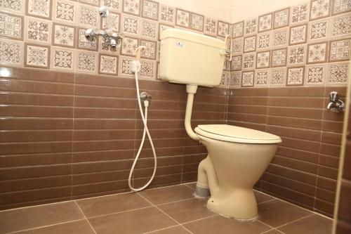 a bathroom with a toilet with a hose at Sudha Grand Guestinn in Nellore