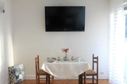 une table blanche avec des chaises et une télévision murale dans l'établissement Moderne Apartement La Defense Paris, à Courbevoie