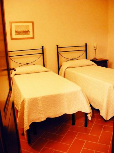a room with two beds with white sheets on them at Relais Villa Sensano in Pignano