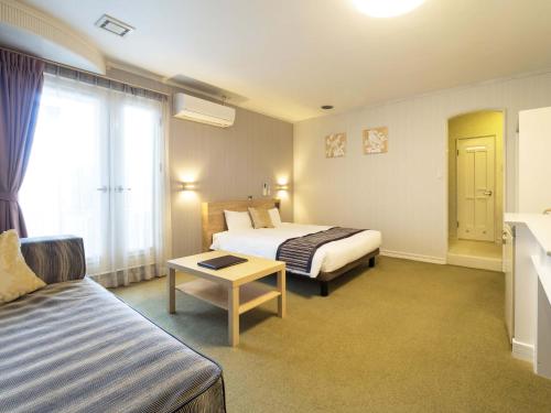 a hotel room with two beds and a couch at Hotel AreaOne Obihiro in Obihiro