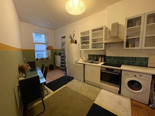 a kitchen with white cabinets and a washer at Urban Grand Suite in Berlin