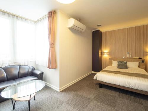 a hotel room with a bed and a couch at Hotel AreaOne Obihiro in Obihiro