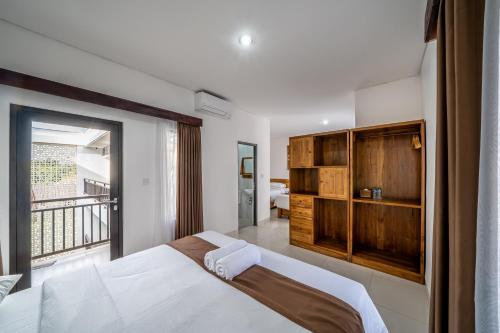 a bedroom with a large bed and a balcony at Sachi Guest House in Jimbaran