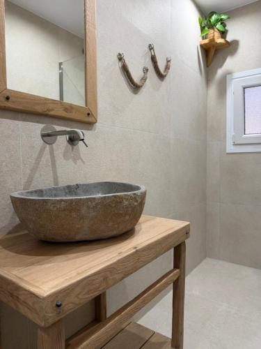 a bathroom with a stone sink on a wooden counter at Alkyonis Apartment Milos in Triovasálos