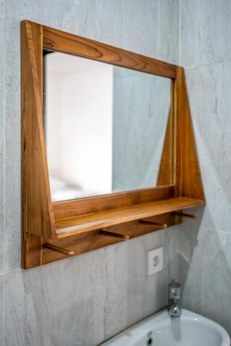 a mirror on a wall above a bathroom sink at Sachi Guest House in Jimbaran