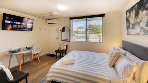 a bedroom with a bed and a table and a window at AZA Motel in Lismore